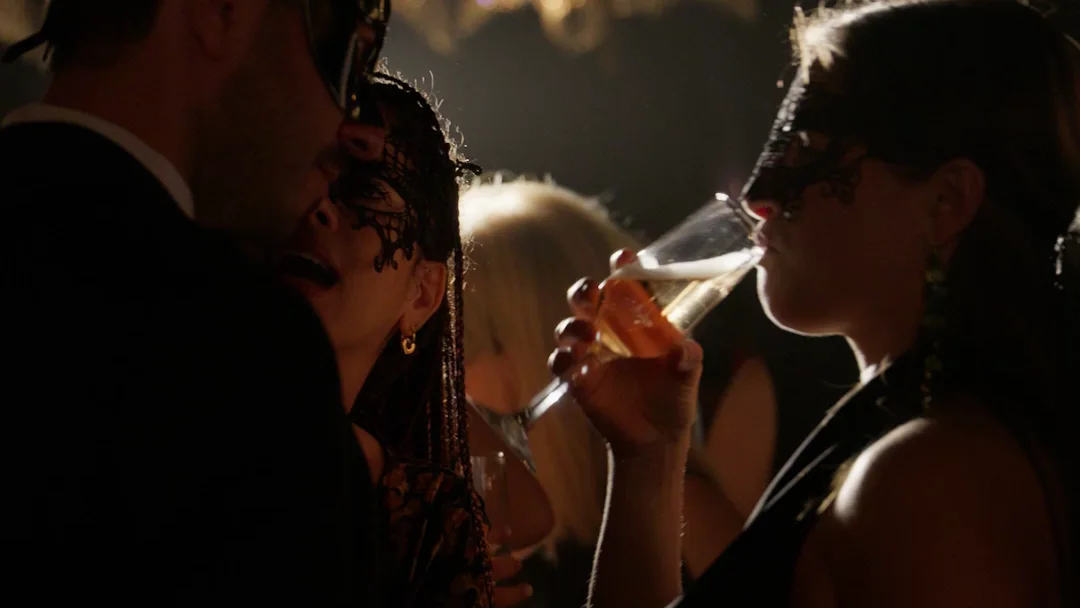Masked guests with champagne under the chandeliers